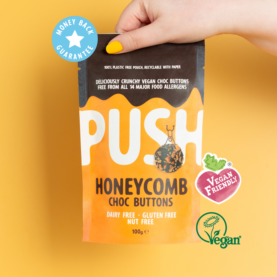 Holding a pouch of Push honeycomb dairy free chocolate buttons - with vegan certified badge. 