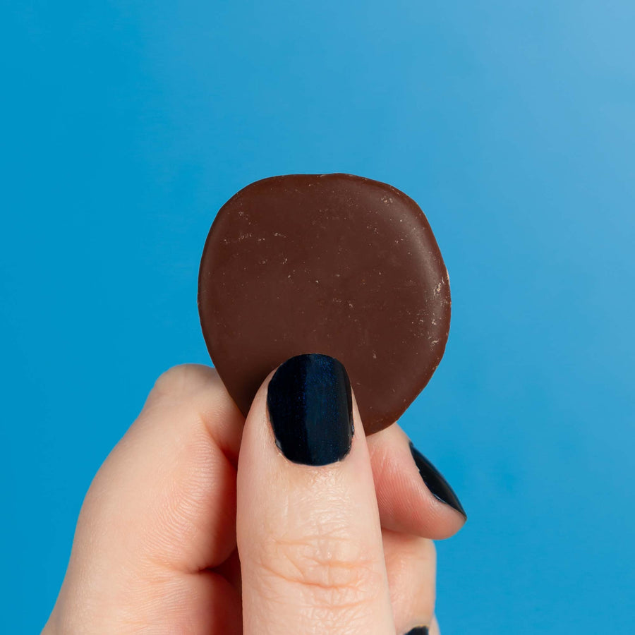 Close up of the low sugar original vegan chocolate button in front of a blue backdrop. 