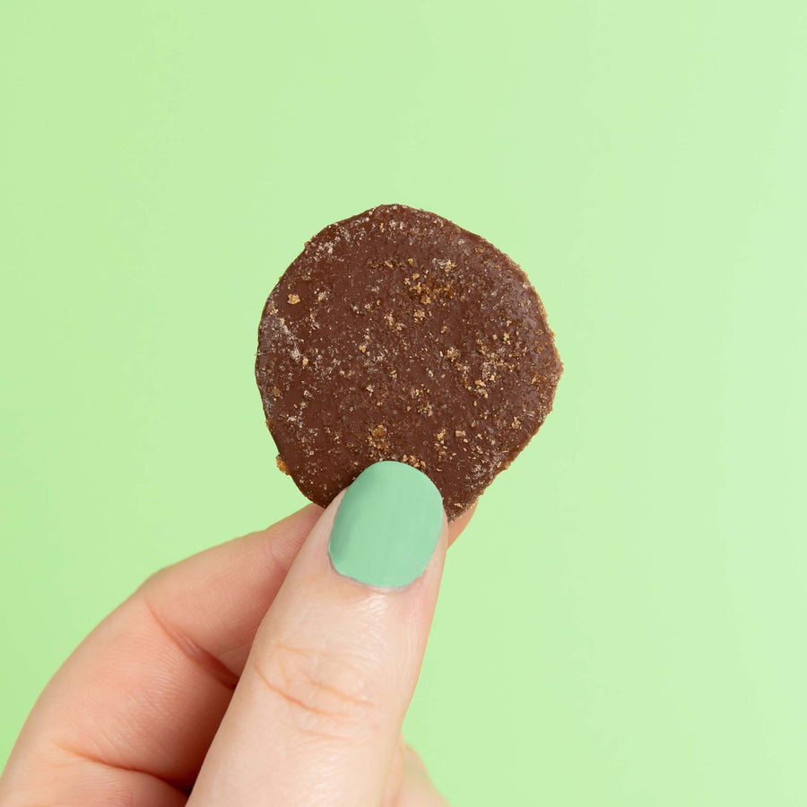 Close up of a mint dairy-free chocolate button on a green backdrop.