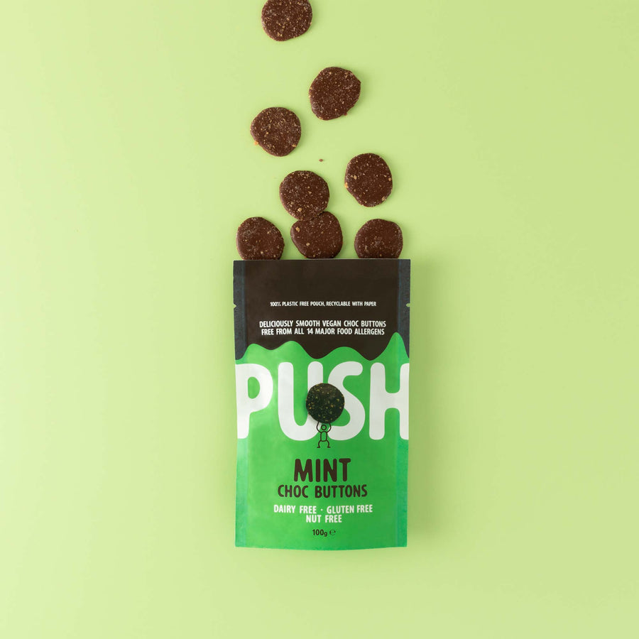 Push Chocolate Mint Chocolate Buttons pictured on a green backdrop with dairy-free chocolate buttons coming out the top of the packaging.