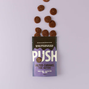 Push Chocolate Salted Caramel Chocolate Buttons pictured on a purple backdrop with dairy-free chocolate buttons coming out the top of the packaging.
