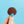 Close up shot of a original vegan chocolate button held by thumb and finger on blue backdrop. 